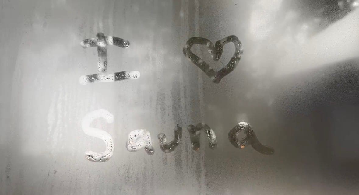 “I love sauna” drawn with a finger in the condensation on a steamed-up sauna window